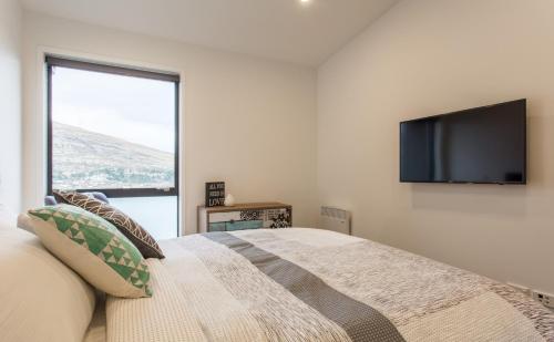 a bedroom with a bed and a flat screen tv at Highland Views in Queenstown