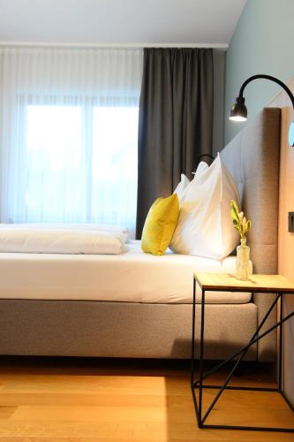 a bed with yellow and white pillows and a window at Landgasthof Sagenhaft in Klagenfurt