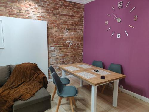 a dining room with a table and a clock on a wall at 1904 Loft in Świnoujście