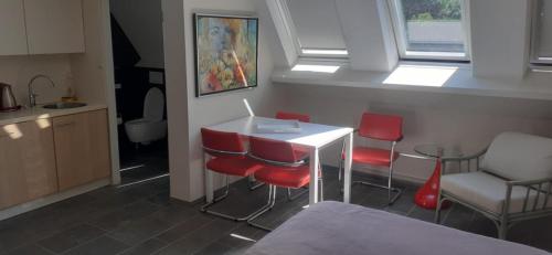 a kitchen with red chairs and a white table at Residentie Kabine 7 in Mellet