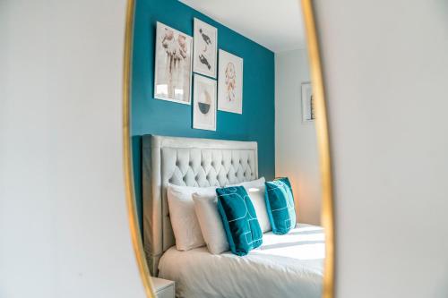 a mirror reflecting a bedroom with a bed with blue walls at Quirky, Family Home in Glasgow in Cardonald