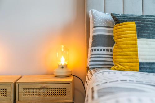 a bed with colorful pillows and a lamp on a table at Quirky, Family Home in Glasgow in Cardonald