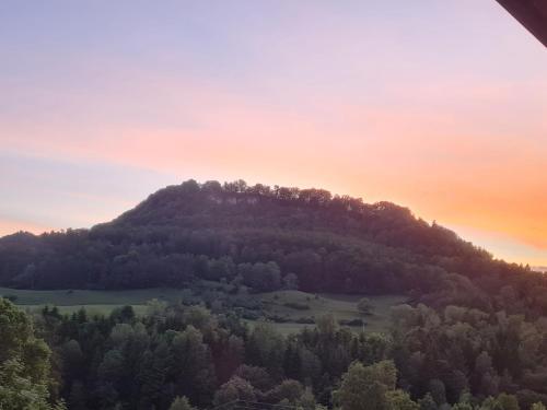 a mountain with trees and a sunset in the background at Ferienwohnung Felsenblick in Albstadt
