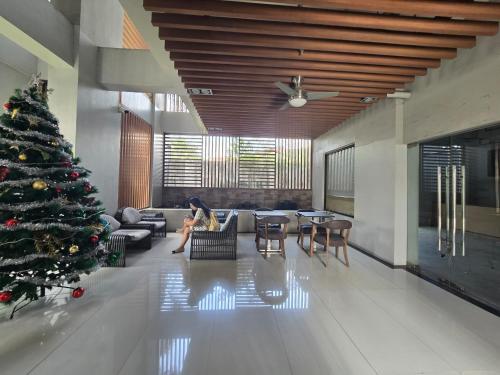 una mujer sentada en una sala de estar con un árbol de Navidad en Ohana Suites 2 Studio Lot 8 Condo Near Ayala Cebu City with fast Wifi and Netflix, en Cebú
