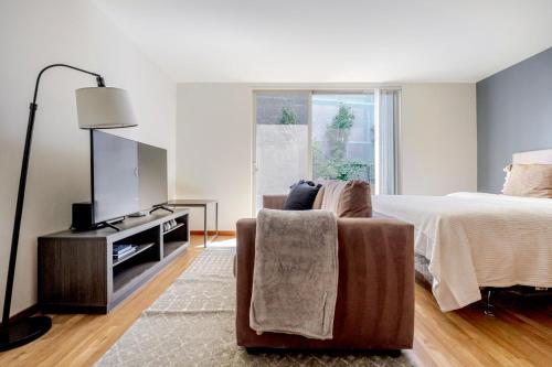 a bedroom with a bed and a tv and a chair at Blueground Brighton balcony nr Seward Park SEA-874 in Seattle
