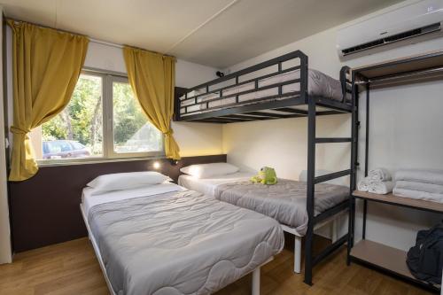 a bedroom with two bunk beds and a window at hu Firenze Certosa camping in town in Impruneta