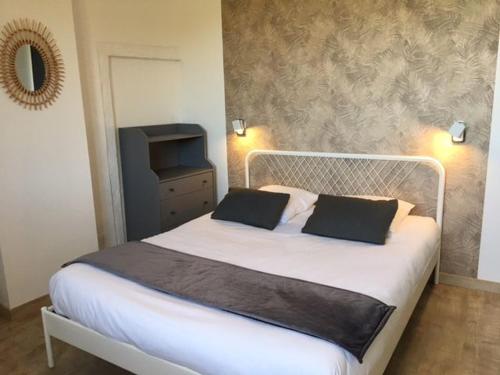 a bedroom with a white bed with two black pillows at Le Mas de Jacquet in Saint-Izaire