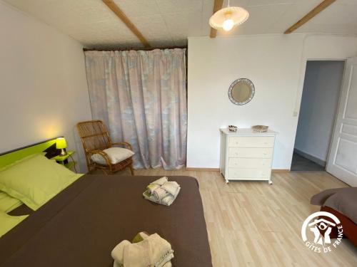 a bedroom with a bed and a chair and a dresser at Gîte entre les Lacs in Curan