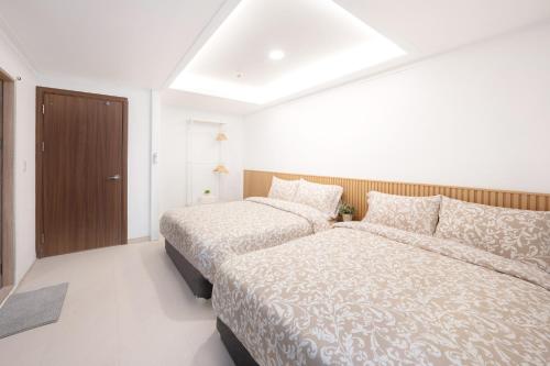 2 camas en una habitación blanca con 2 camas sidx sidx sidx sidx en Seoul Cozy Hostel, en Seúl