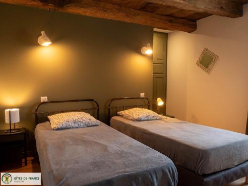 two beds in a room with lights on the wall at Le Grand Gîte in Cassagnes-Bégonhès