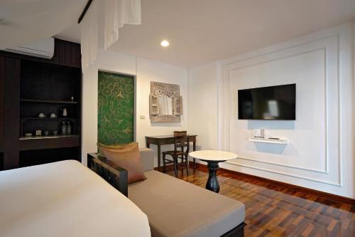 a bedroom with a bed and a table and a tv at Praseban Resort in Pran Buri