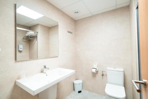 a bathroom with a sink and a toilet and a mirror at Hotel Europa in Figueres