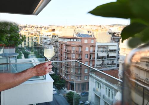 a person holding a glass of wine on a balcony at Icon Central SKG in Thessaloniki