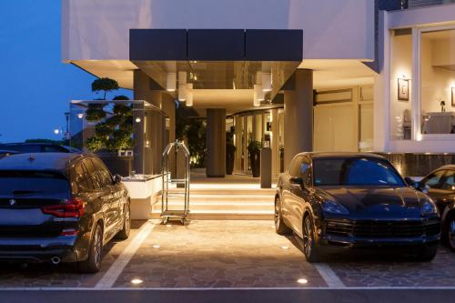 two parked cars parked in front of a building at Hotel Mariver in Lido di Jesolo