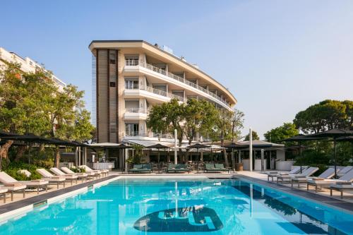 a swimming pool with chairs and a hotel at Hotel Mariver in Lido di Jesolo