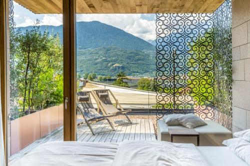 a bedroom with a bed and a balcony with a view at Hotel Muchele in Postal