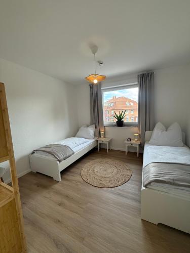 two beds in a room with a window at Ildiz Ferienwohnungen in Wiefelstede