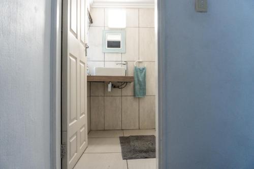 a bathroom with a sink and a mirror and a door at The Zinkwazi Beach Holiday Home in Zinkwazi Beach