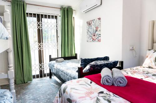 a bedroom with two beds and a window with green curtains at The Zinkwazi Beach Holiday Home in Zinkwazi Beach