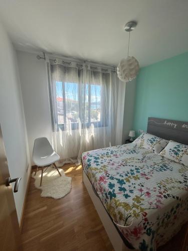 a bedroom with a bed and a chair and a window at La Isla in Isla de Arosa