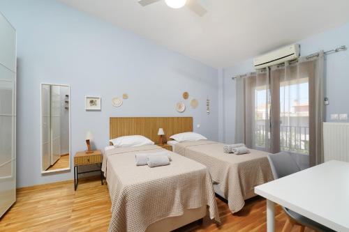 two beds in a room with white walls and wooden floors at Villa Olia in Nea Roda