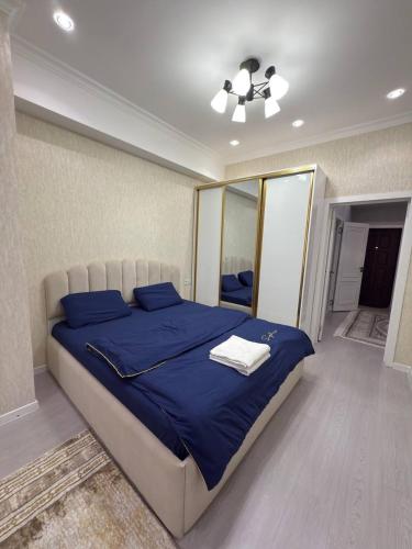 a bedroom with a bed with blue sheets and a ceiling fan at The Pearl in Dushanbe