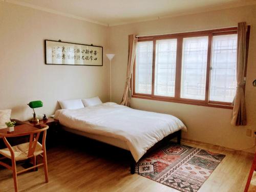 a bedroom with a bed and a table and a window at A spacious, cosy, independent house in Pohang