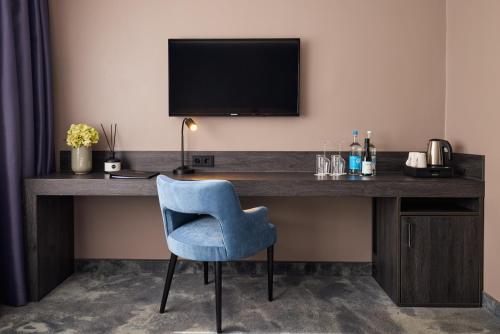 a desk with a blue chair and a television at Hotel du Nord Alster - auf der Uhlenhorst - SELF CHECK-IN in Hamburg