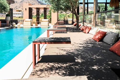 a row of benches next to a swimming pool at Ikaros Suites in Amoudara Herakliou