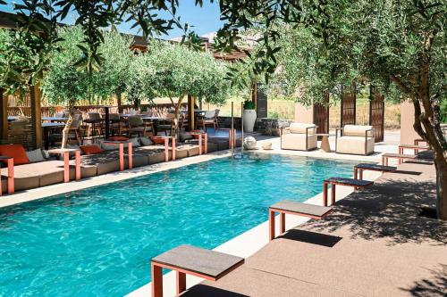 a large swimming pool with lounge chairs and trees at Ikaros Suites in Amoudara Herakliou