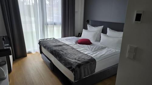 a bedroom with a bed with a red pillow on it at Frames Hotel GmbH in Mülheim-Kärlich