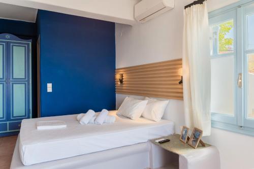 a bedroom with a white bed with a blue wall at La Casa Tinos 22 in Agios Ioannis Tinos
