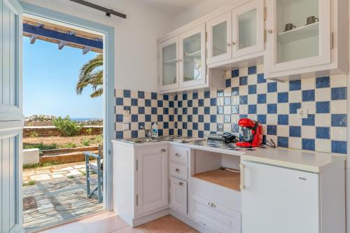 a kitchen with white cabinets and a view of the ocean at La Casa Tinos 22 in Agios Ioannis Tinos
