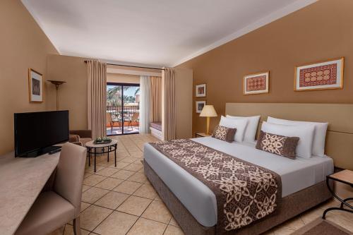 a hotel room with a bed and a television at JAZ Makadi Saraya Resort in Hurghada