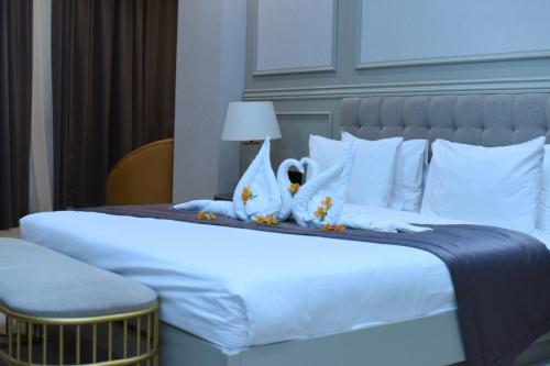 a bedroom with a large white bed with two swans on it at Horizon Manor Hotel in Doha