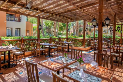 an outdoor restaurant with wooden tables and chairs at JAZ Makadi Saraya Resort in Hurghada