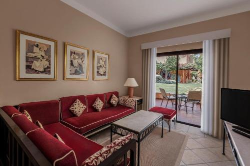 a living room with a red couch and a television at JAZ Makadi Saraya Resort in Hurghada