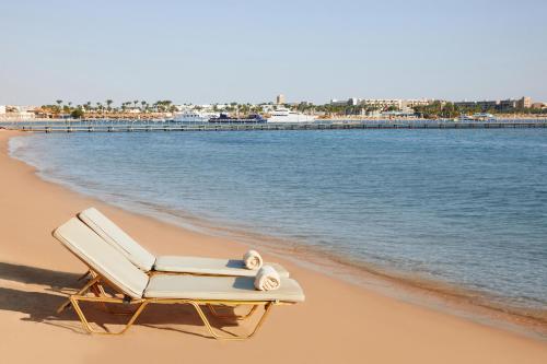 a beach chair sitting on a beach next to the water at JAZ Makadi Saraya Resort in Hurghada