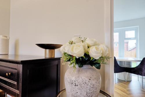 a white vase filled with white roses on a table at Luxury and cosy 2 bed entire house in Essex 20 mins from beach in Colchester
