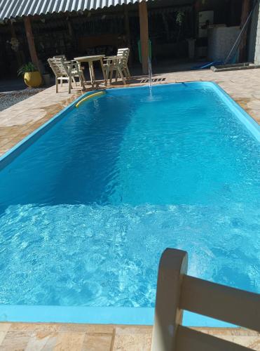 a blue swimming pool with a table and chairs at Pousada Rota in Paty do Alferes