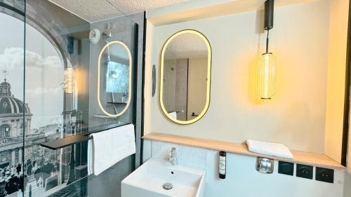 a bathroom with a sink and two mirrors at Campanile Epinay sur Orge Savigny Sur Orge in Épinay-sur-Orge