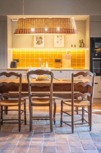 a kitchen with a wooden table and chairs at Le Domaine de Richebourg - Pierres d'Histoire in Richebourg