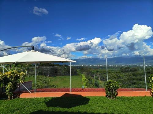 a white umbrella sitting on top of a tennis court at la colombiana casa campestre in Quimbaya