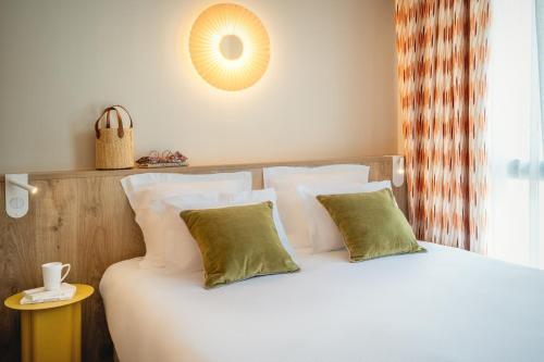 a bedroom with a bed with white sheets and green pillows at La Résidence - Thalazur Arcachon in Arcachon