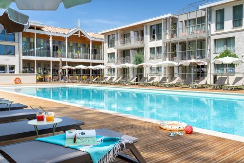 a pool at a hotel with chaise lounge chairs at La Résidence - Thalazur Arcachon in Arcachon
