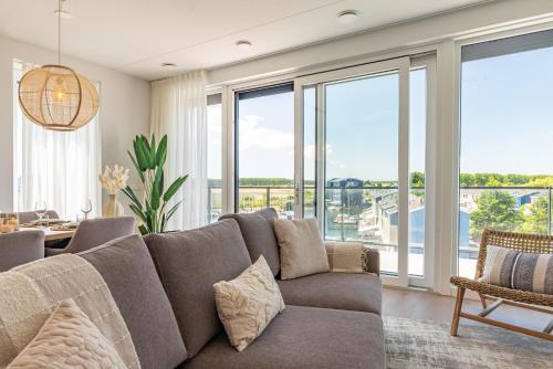 a living room with a large couch and large windows at Appartement Havenzicht 13A Kortgene in Kortgene