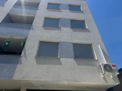 a tall white building with windows and a camera at Duplex City Center Gjakove in Gjakove