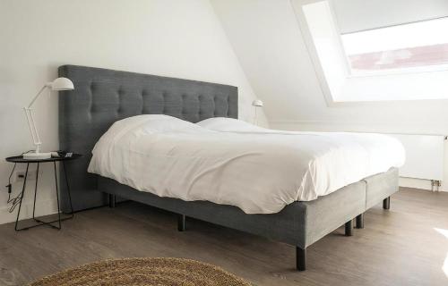 1 dormitorio con 1 cama grande y cabecero gris en G-15 Bouwlust, en De Cocksdorp