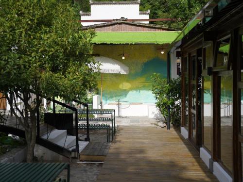 a wooden walkway leading to a patio with an umbrella at Huangshan Hongcun Weizhashan Xunxi Hotel in Huangshan