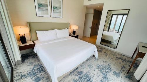a bedroom with a large white bed and a mirror at شقه فاخره في فندق العنوان ثلاث غرف نوم اطلاله علي البحر مباشره in Fujairah